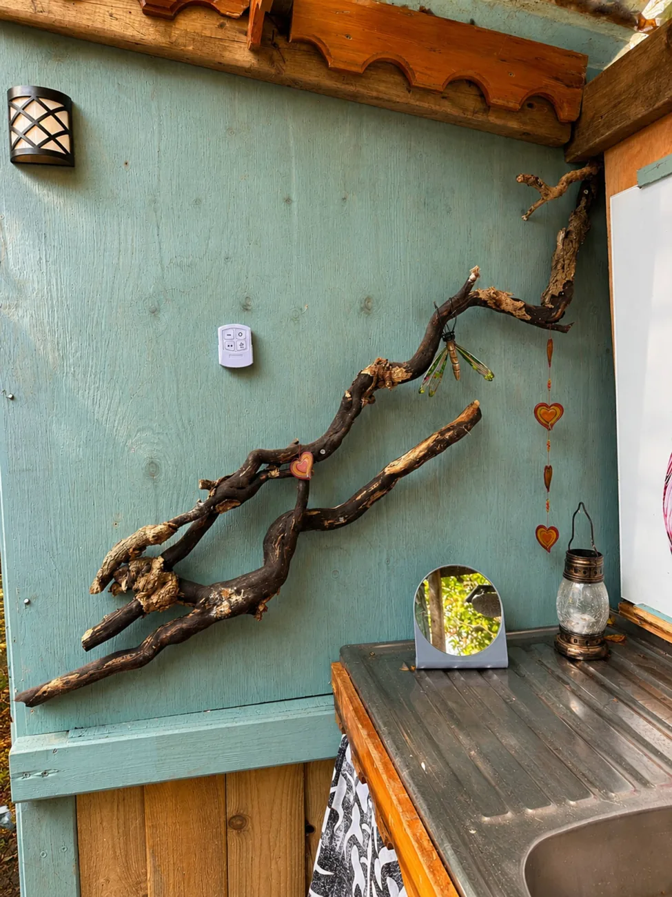 A driftwood branch and lantern against a painted panel by the wash area