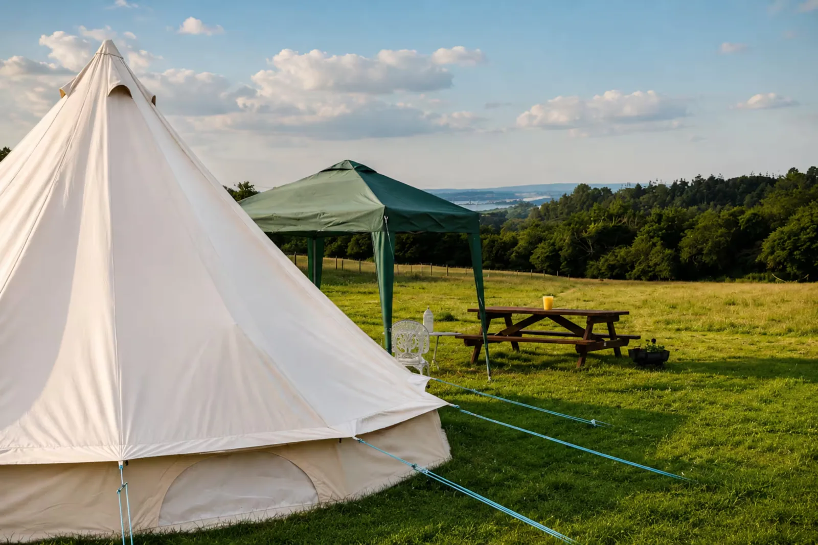 The Bell Tent pitched on the field with a canopy beside it and the countryside beyond