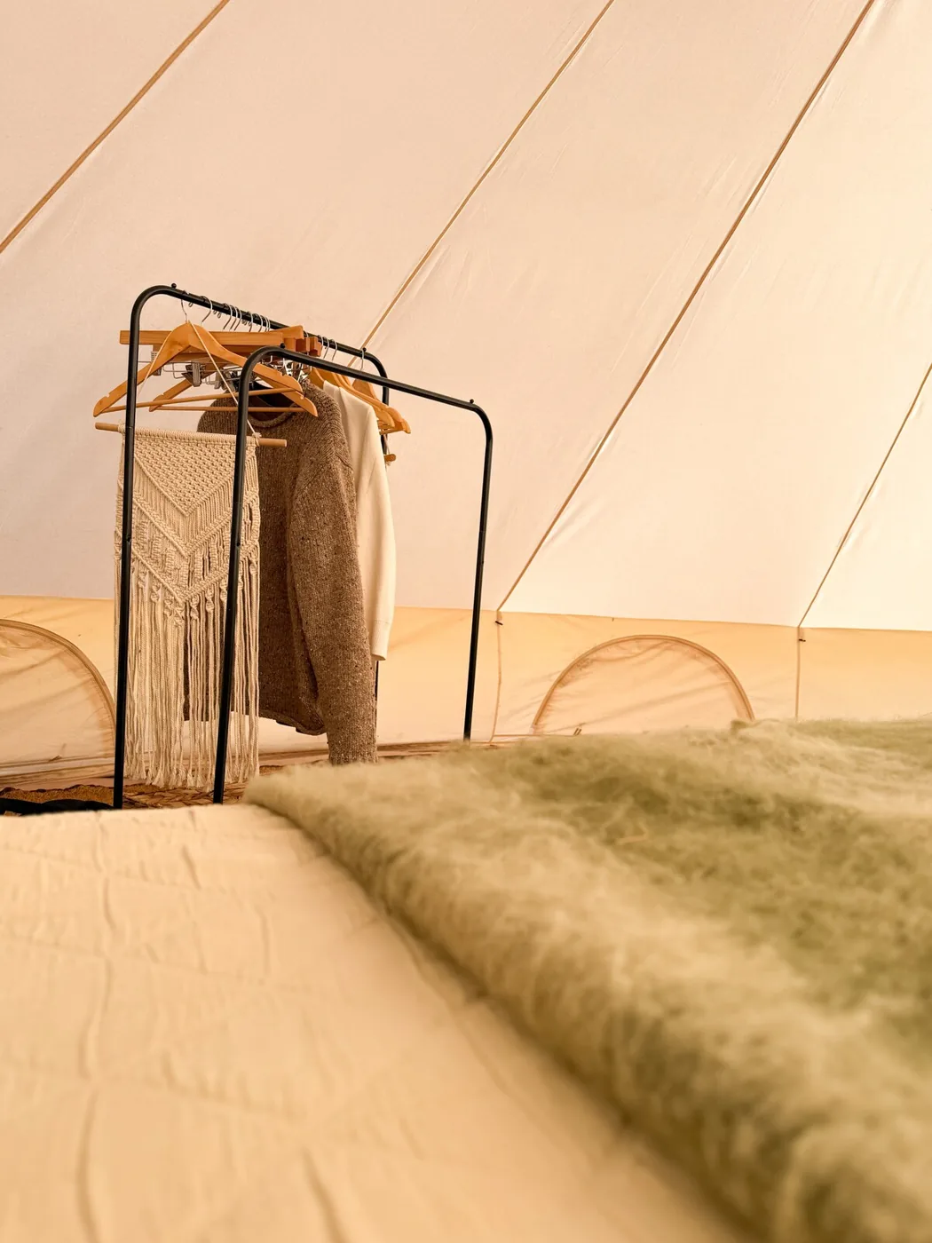 A clothes rail with macramé beside the bed in the Family Tent